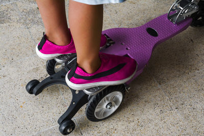 Low section of woman with pink shoes on street