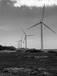 Windmills on field against sky