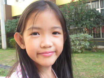 Close-up portrait of smiling girl in yard