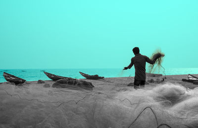 Rear view of man standing on shore against sea