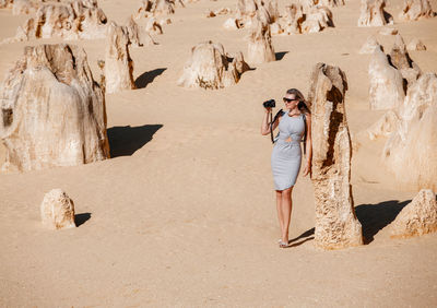 Full length of woman standing by rock formation outdoors