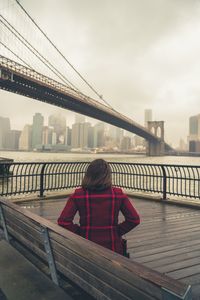 Bridge over river against sky in city