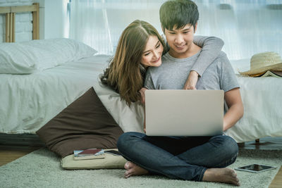 Young woman using laptop while sitting on sofa at home