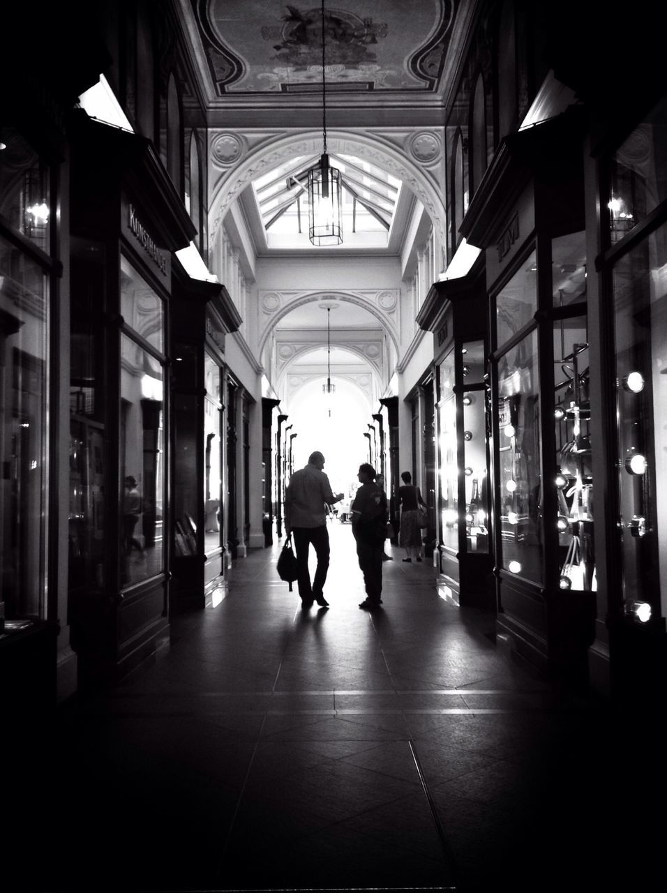 indoors, architecture, men, walking, built structure, person, full length, lifestyles, ceiling, rear view, illuminated, the way forward, corridor, city life, lighting equipment, leisure activity, flooring, architectural column, city