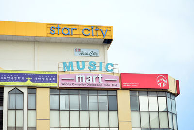 Low angle view of information sign on building against sky