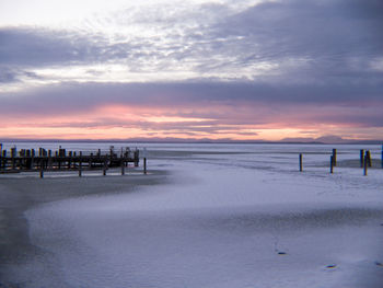 Scenic view of beach against sky at sunset