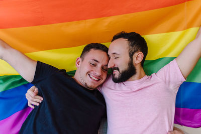 Two homosexual men holding lgbtq flag.