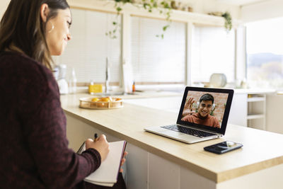 Businesswoman doing video call with colleague on laptop at home