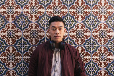 Portrait of young man standing against wall