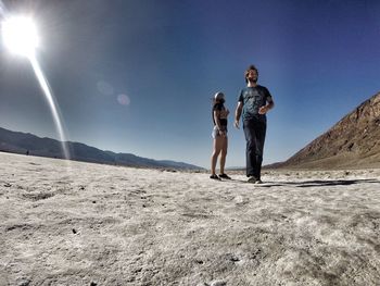 Full length of friends walking on landscape against sky