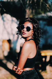 Portrait of young woman wearing sunglasses standing outdoors