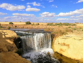 Scenic view of waterfall against sky