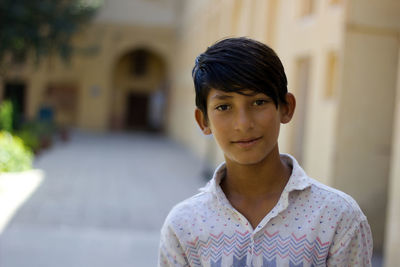 Portrait of boy standing against building