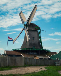 In front of a windmill in zaanse schans with a dutch flag floating in the wind