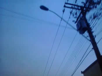 Low angle view of power lines against blue sky