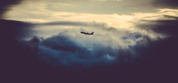 Low angle view of airplane flying against cloudy sky