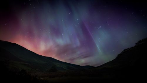 Scenic view of silhouette mountains against sky at night