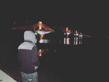 Rear view of woman standing against illuminated sky at night