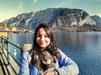 Portrait of smiling young woman standing on mountain against sky