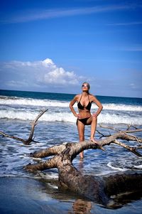 Rear view of woman standing on beach against sky