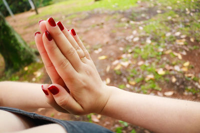 Midsection of woman doing yoga with hands clasped on field