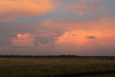 Scenic view of agricultural field against sky at sunset