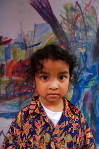 Portrait of cute girl behind a painting on the wall