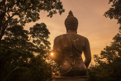 Low angle view of buddha statue against sky during sunset