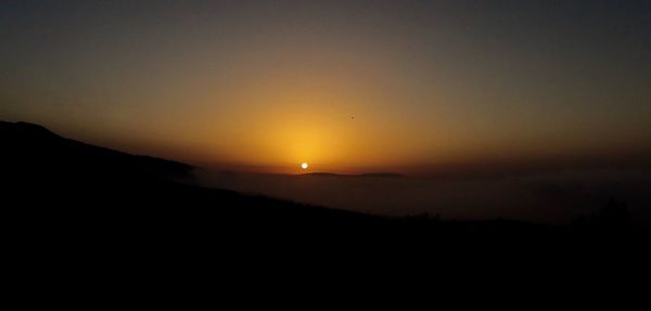 Scenic view of silhouette mountains against clear sky during sunset