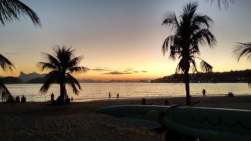 Silhouette palm trees on beach against sky during sunset