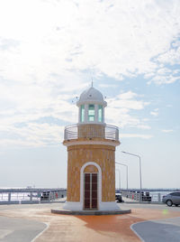 Lighthouse by sea against sky