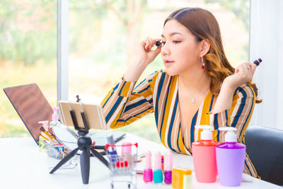 Young woman looking away while sitting on table