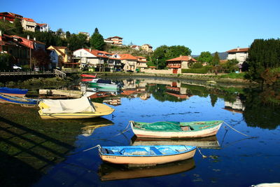 Boats moored in lake against clear blue sky