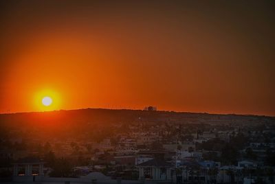 Scenic view of townscape against orange sky