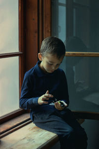 Rear view of boy looking through window