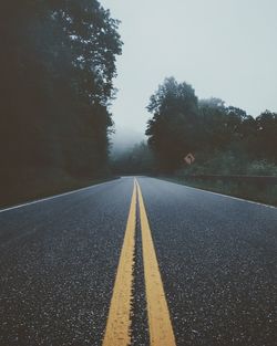 Road amidst trees against clear sky