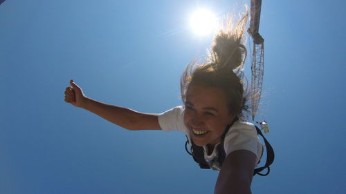 Low angle view of girl against clear blue sky