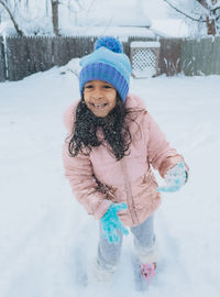 Diverse mixed race pre school toddler girl outdoors in winter playing with snow 