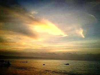 Scenic view of sea against cloudy sky at sunset