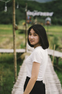 Portrait of smiling young woman standing on boardwalk