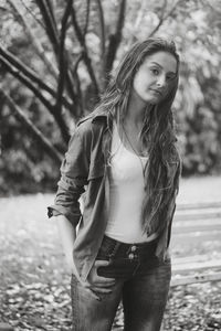 Portrait of young woman standing against tree