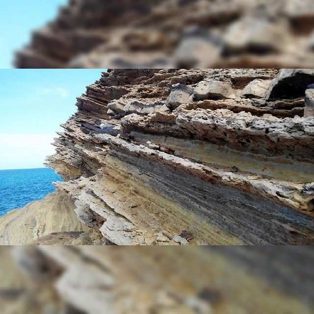 textured, wood - material, focus on foreground, sea, beach, close-up, rough, nature, rock - object, tranquility, sky, selective focus, day, tranquil scene, rock formation, outdoors, wood, weathered, shore, brown