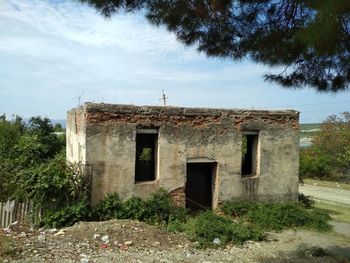 Abandoned house on field against sky