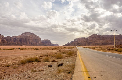 Road leading towards mountains against sky