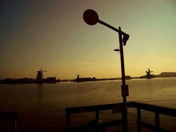 Silhouette pier by sea against clear sky during sunset
