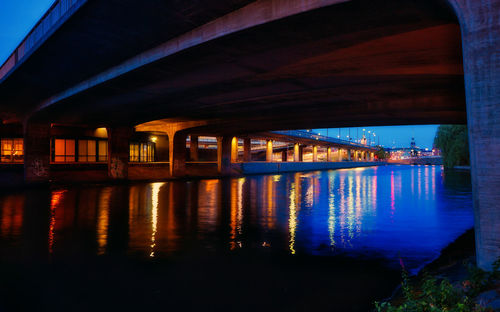 Illuminated bridge over river against sky at night