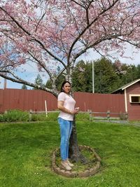 Portrait of young woman standing on grass against trees