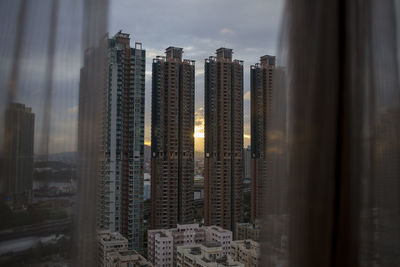 Modern buildings against sky seen through glass window, hong kong