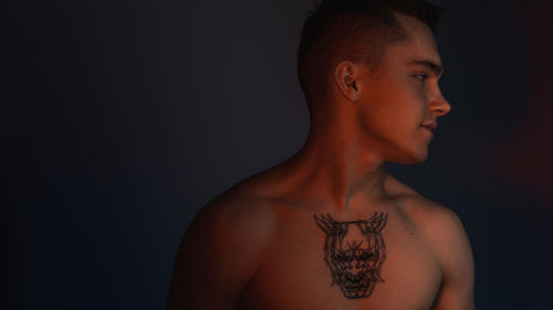 Portrait of young man looking away against black background