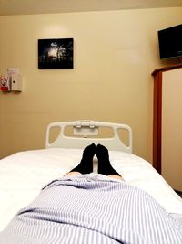 Low section of person relaxing on bed at home